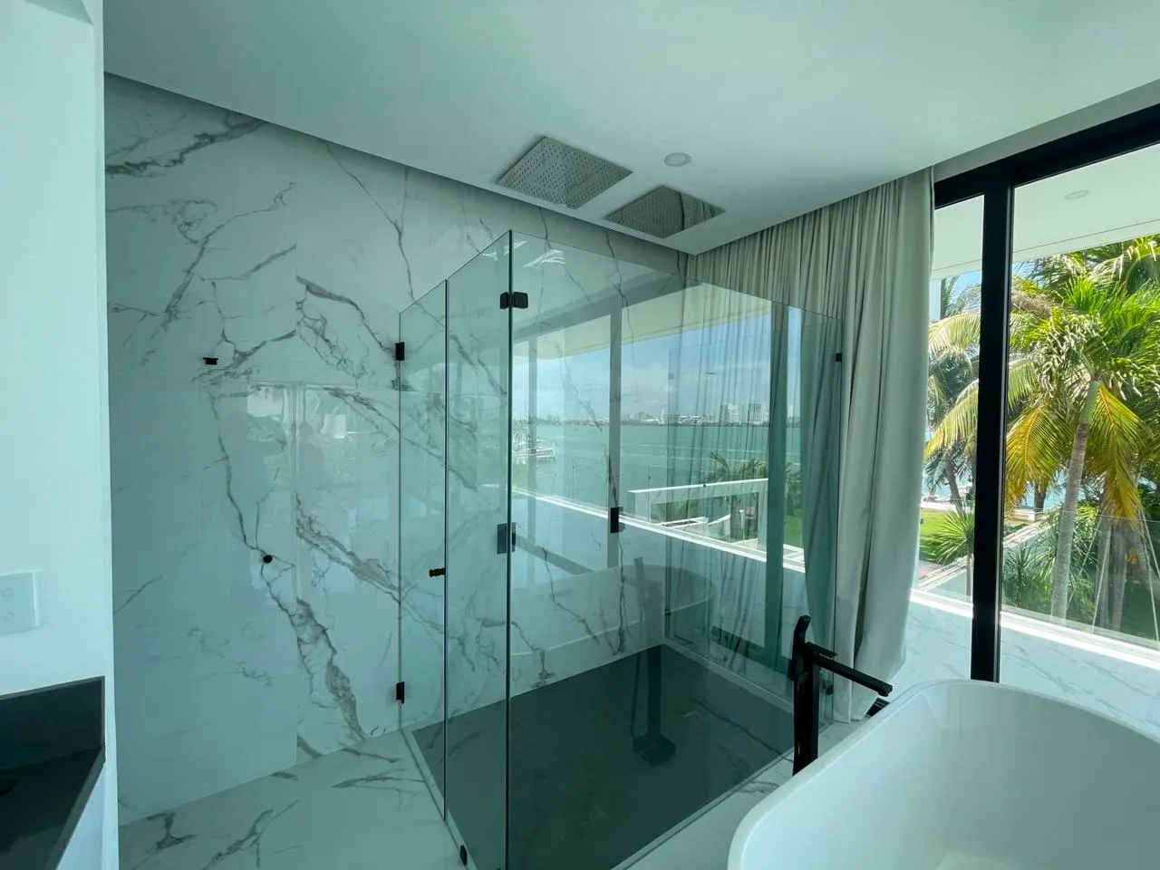 Cancel de baño en cristal templado con herrajes negros y vista a laguna