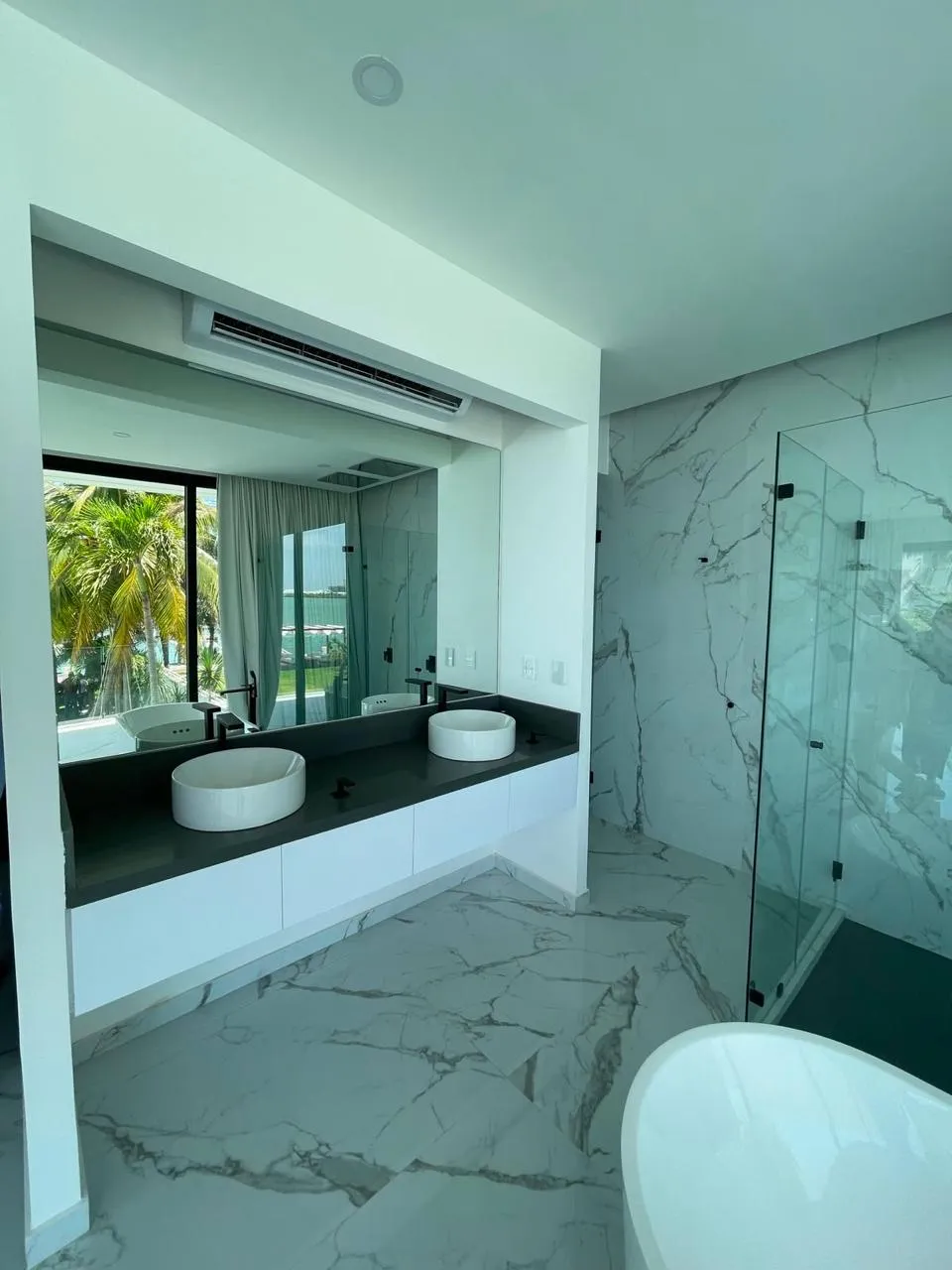 Baño de mármol con cancel de cristal templado y doble lavabo