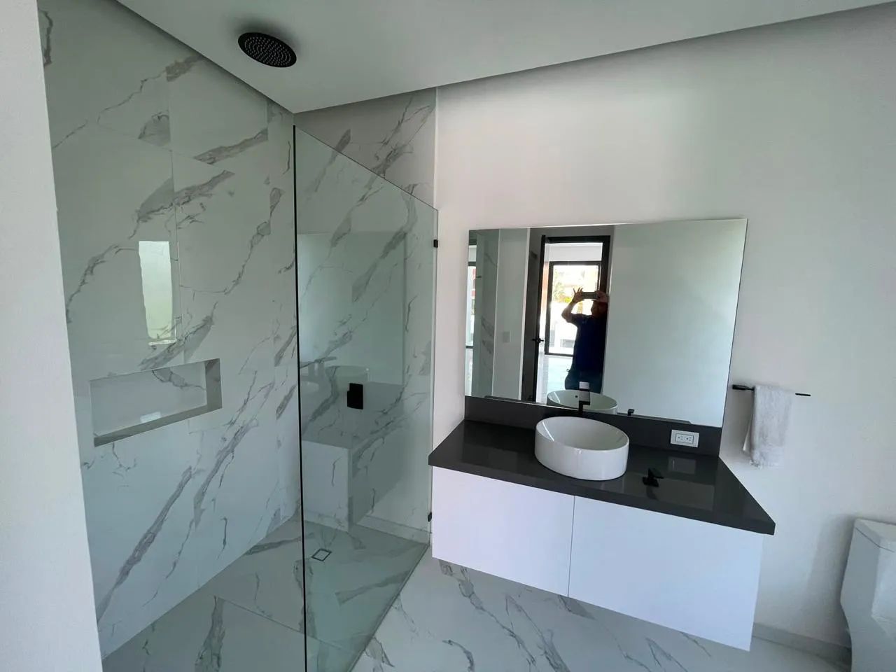Cancel fijo de cristal templado en baño de mármol con lavabo
