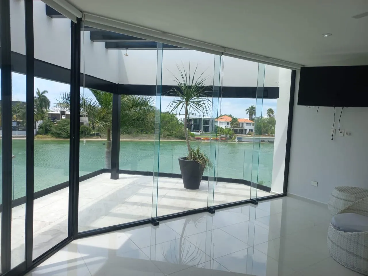 Sala con muro de cristal templado sin marco y vista a jardín en Mérida