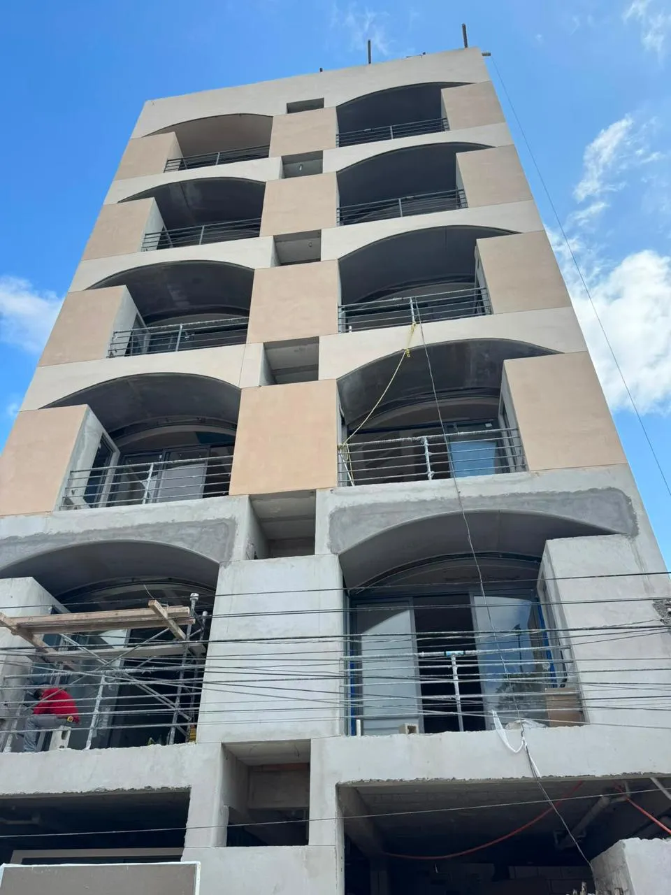 Fachada de edificio de departamentos en construcción con balcones curvos