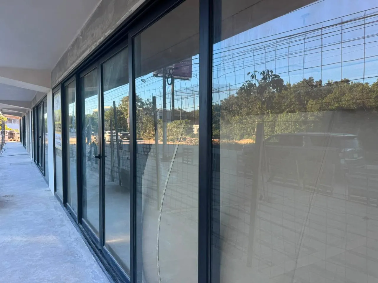 Fachada comercial con cancelería corrediza de aluminio negro y cristal