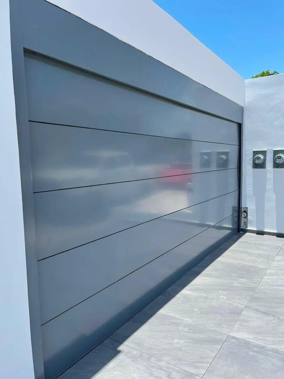 Portón corredizo de aluminio color gris en cochera residencial
