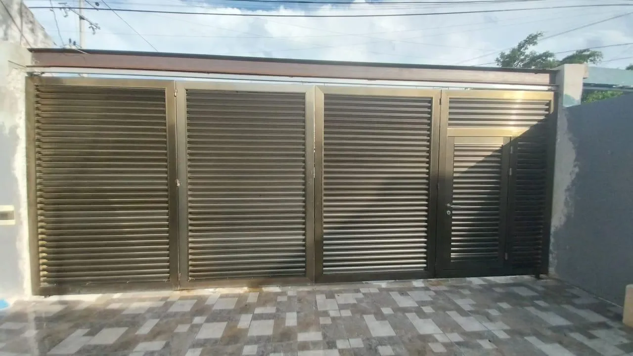 Portón de herrería con celosía metálica y puerta peatonal integrada