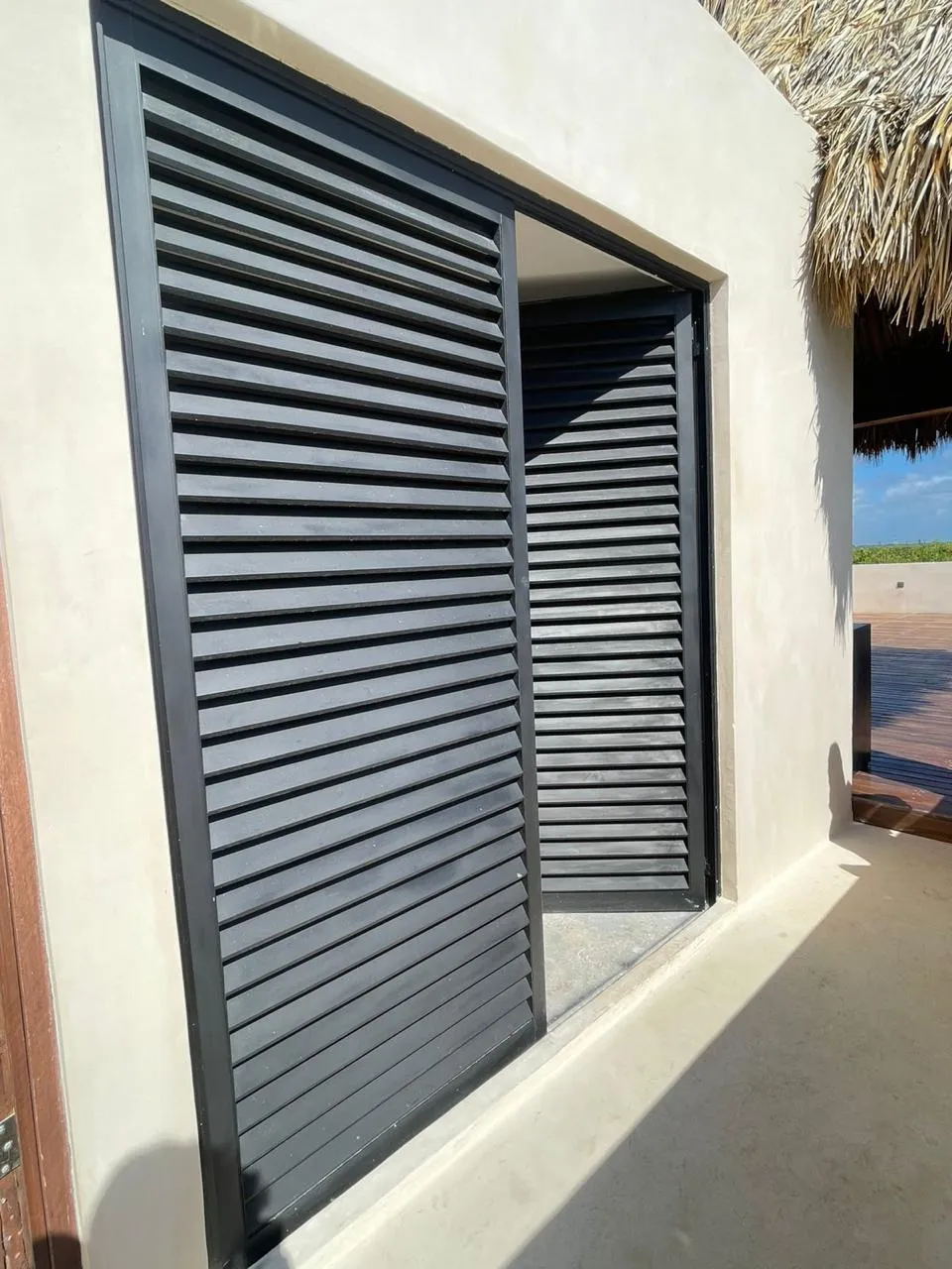 Persianas fijas de aluminio negro en terraza con techo de palapa