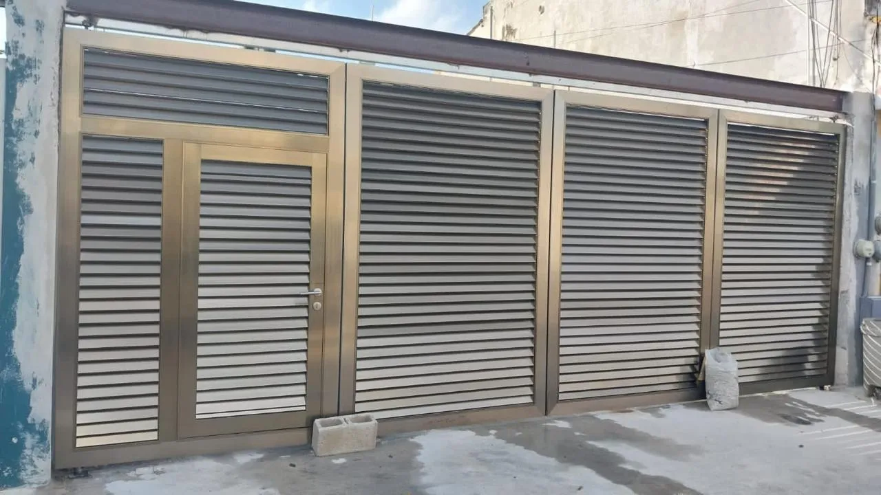 Portón de persiana metálica color champán con puerta peatonal