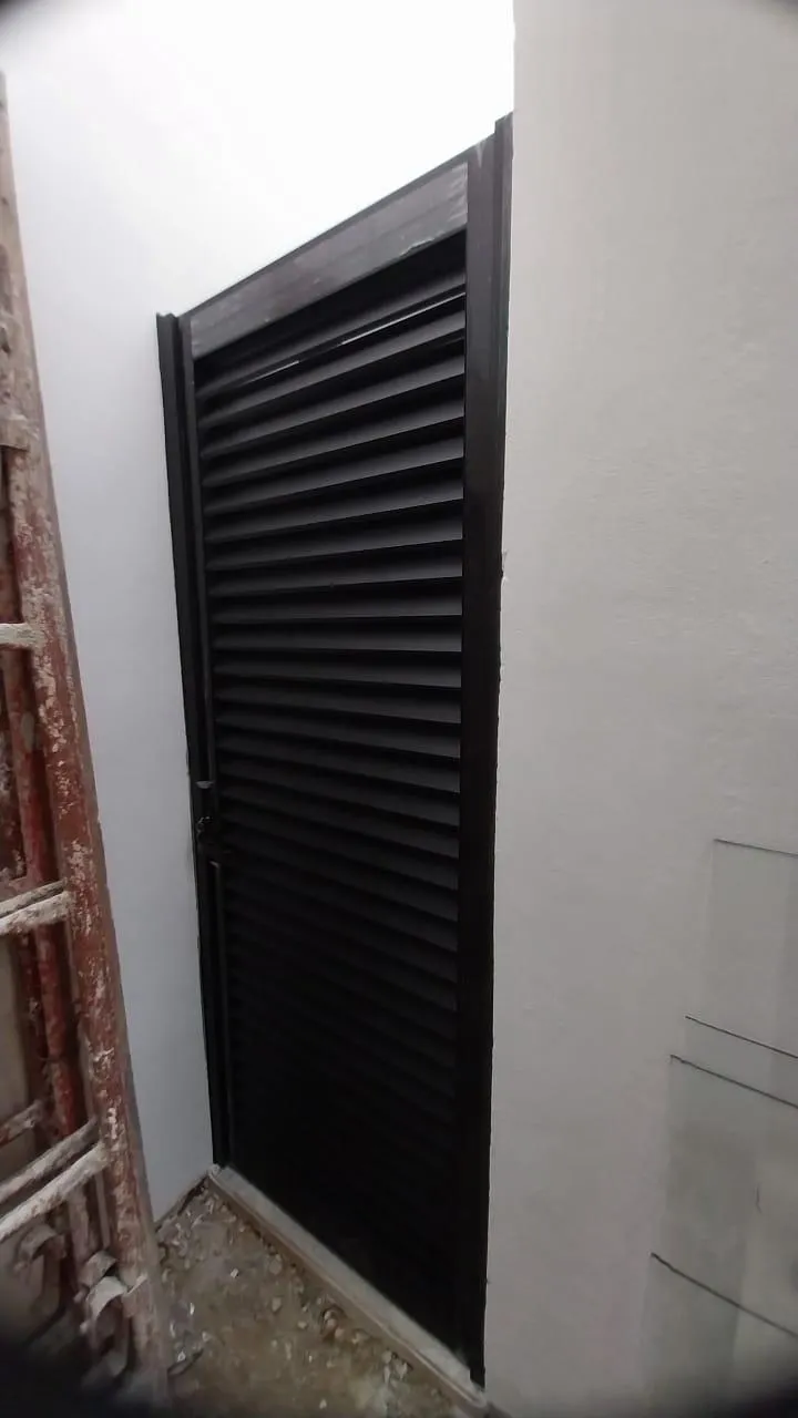 Puerta de persiana de aluminio negro en paso de servicio
