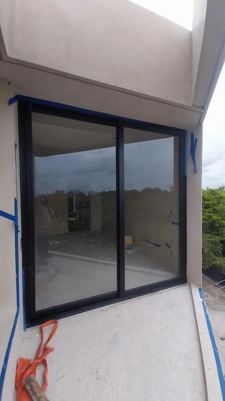 Ventana corrediza de aluminio negro en obra con vista a selva