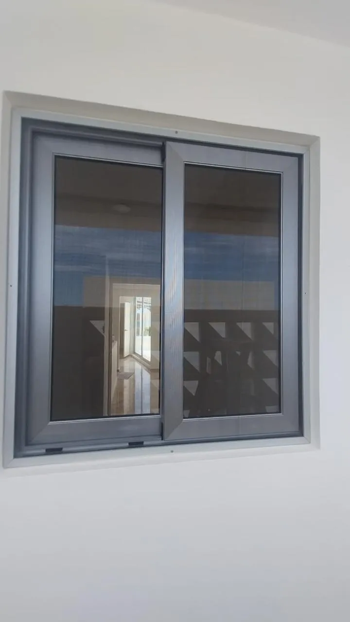 Ventana corrediza de aluminio gris con mosquitero en vista interior