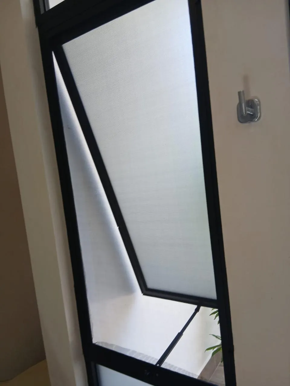 Detalle de ventana proyectante de aluminio negro con mosquitero