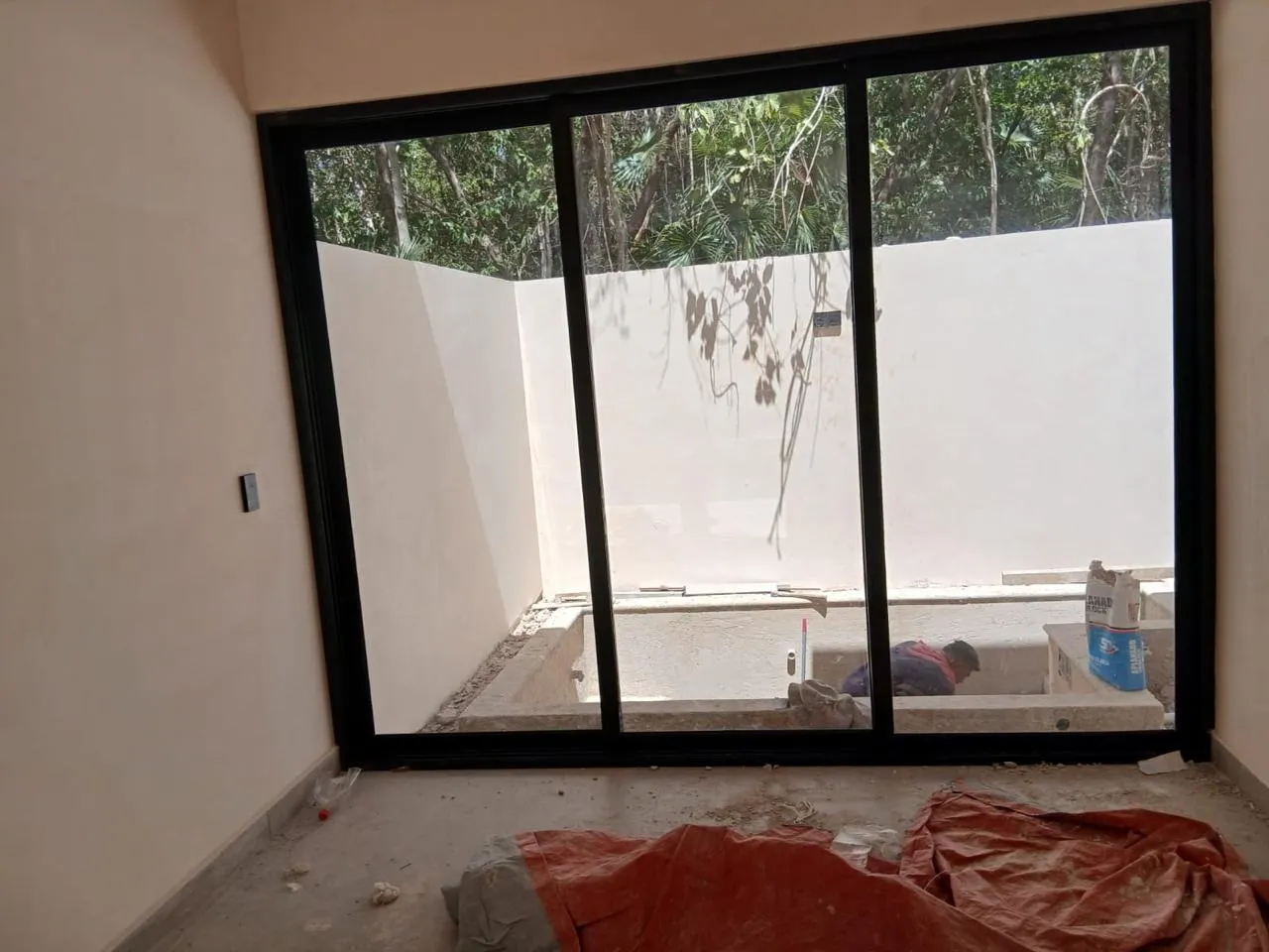 Ventanal corredizo de aluminio negro de tres hojas con vista a selva