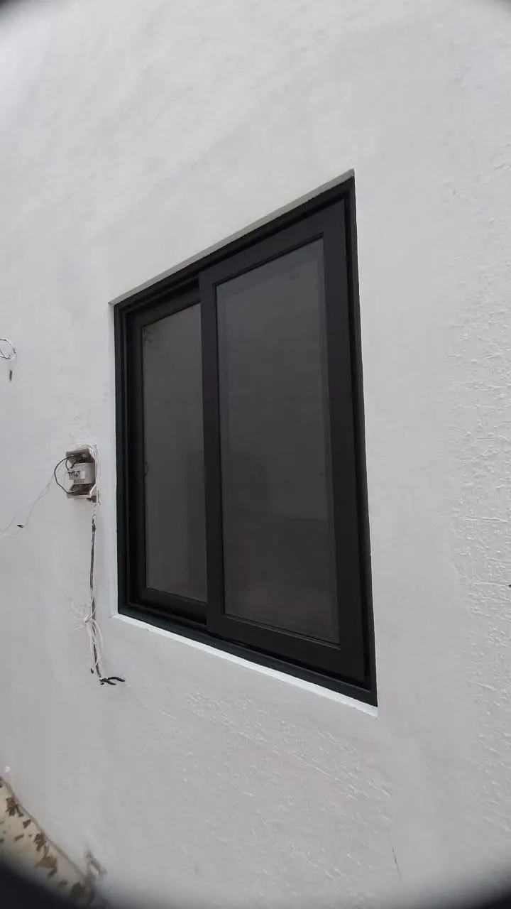 Ventana corrediza de aluminio negro en muro exterior blanco