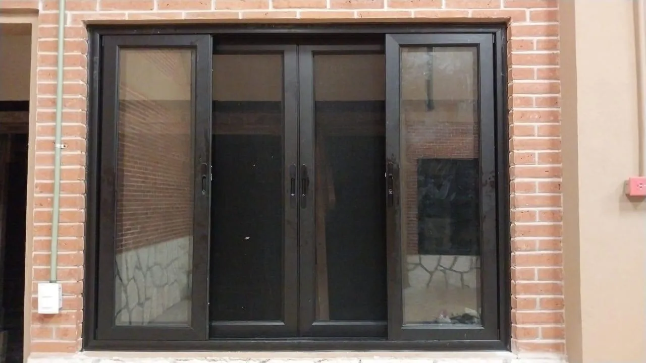 Ventanal de aluminio café con cristal sobre muro de ladrillo