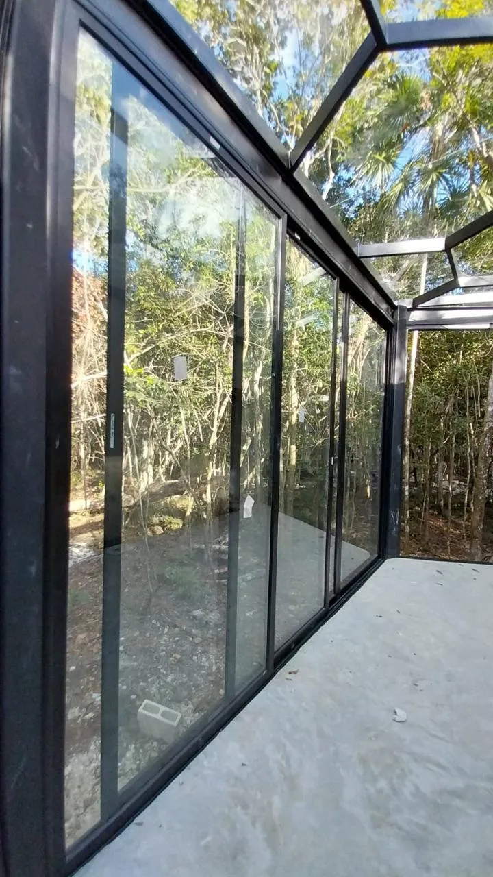 Domo acristalado de aluminio negro con techo inclinado en selva