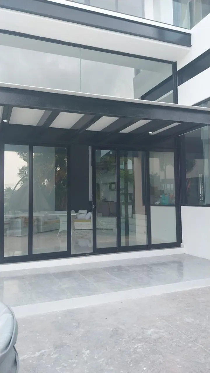 Cancelería corrediza de aluminio negro bajo pórtico en patio residencial
