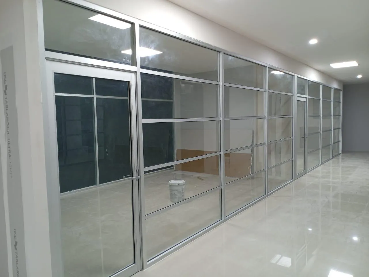 División de oficina en aluminio y cristal en pasillo iluminado