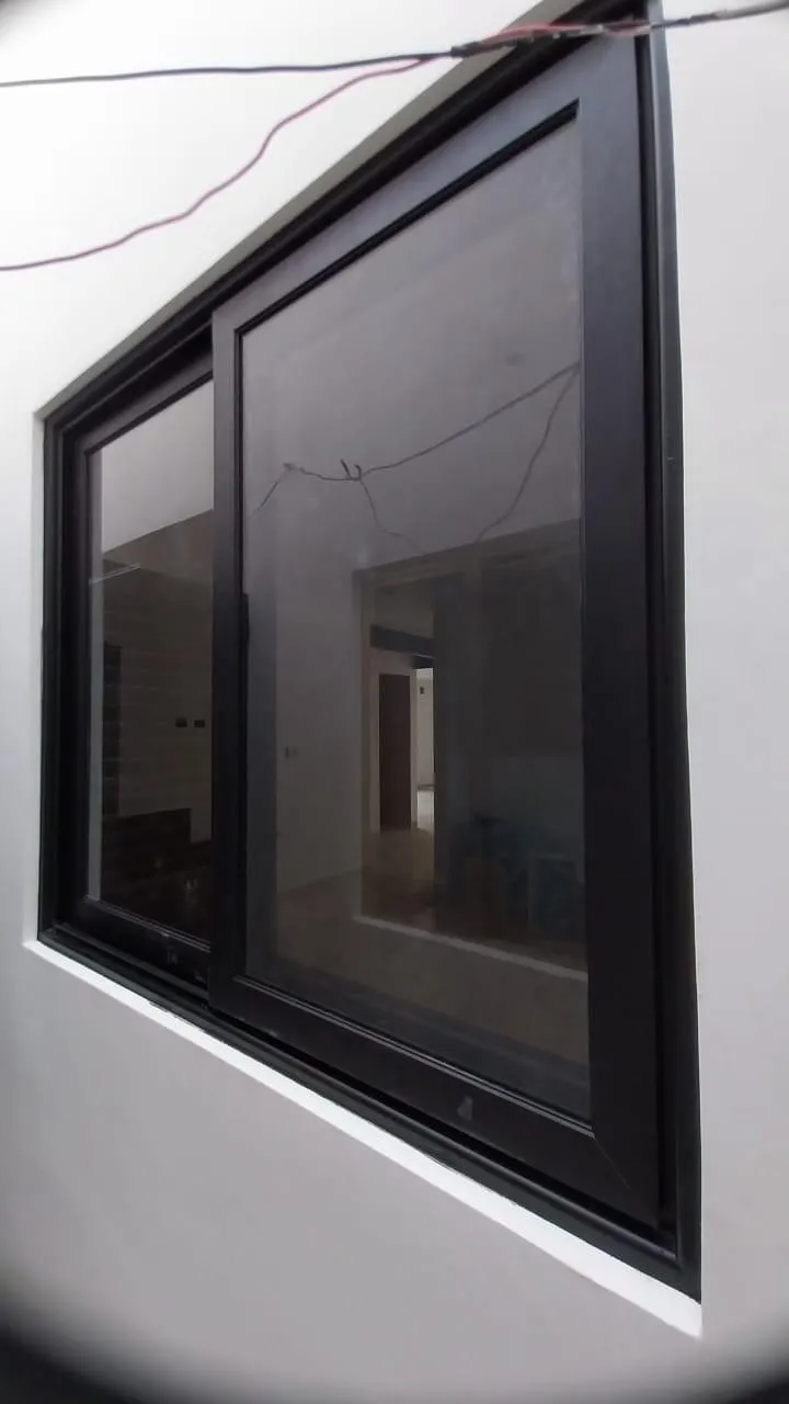 Ventana corrediza de aluminio negro vista desde el exterior en obra
