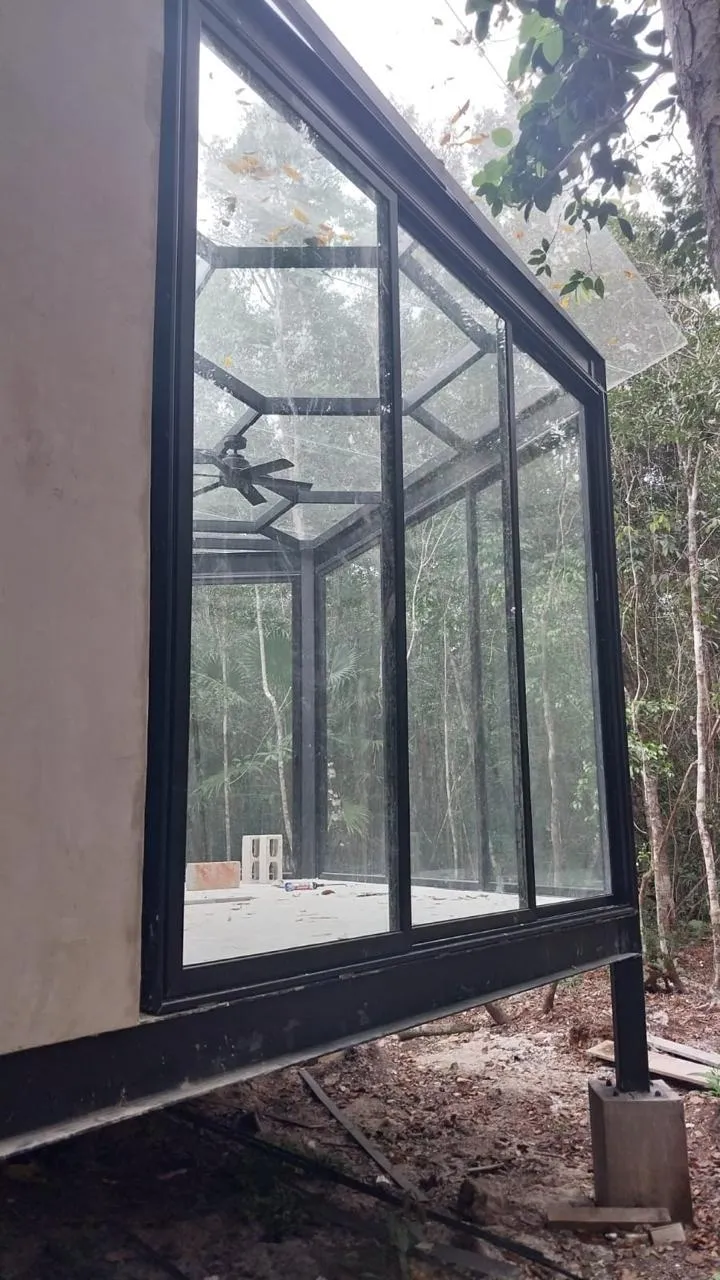 Galería acristalada de aluminio negro con techo inclinado en selva