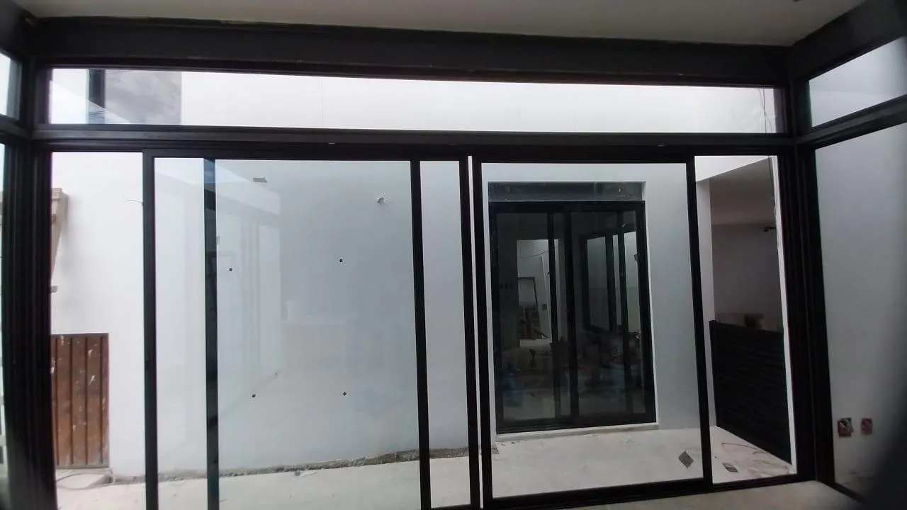 Cancelería fija de aluminio negro en esquina interior en obra