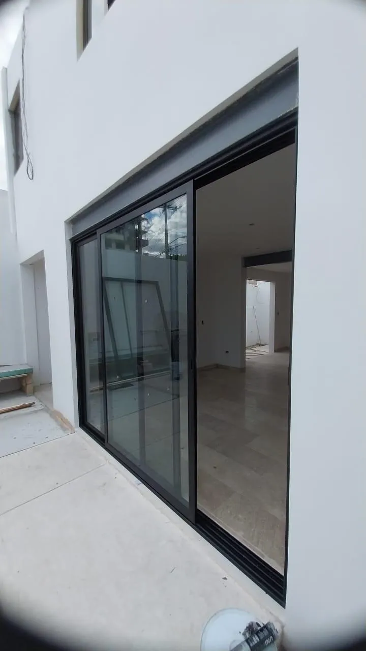 Puerta corrediza de aluminio negro vista desde patio en obra