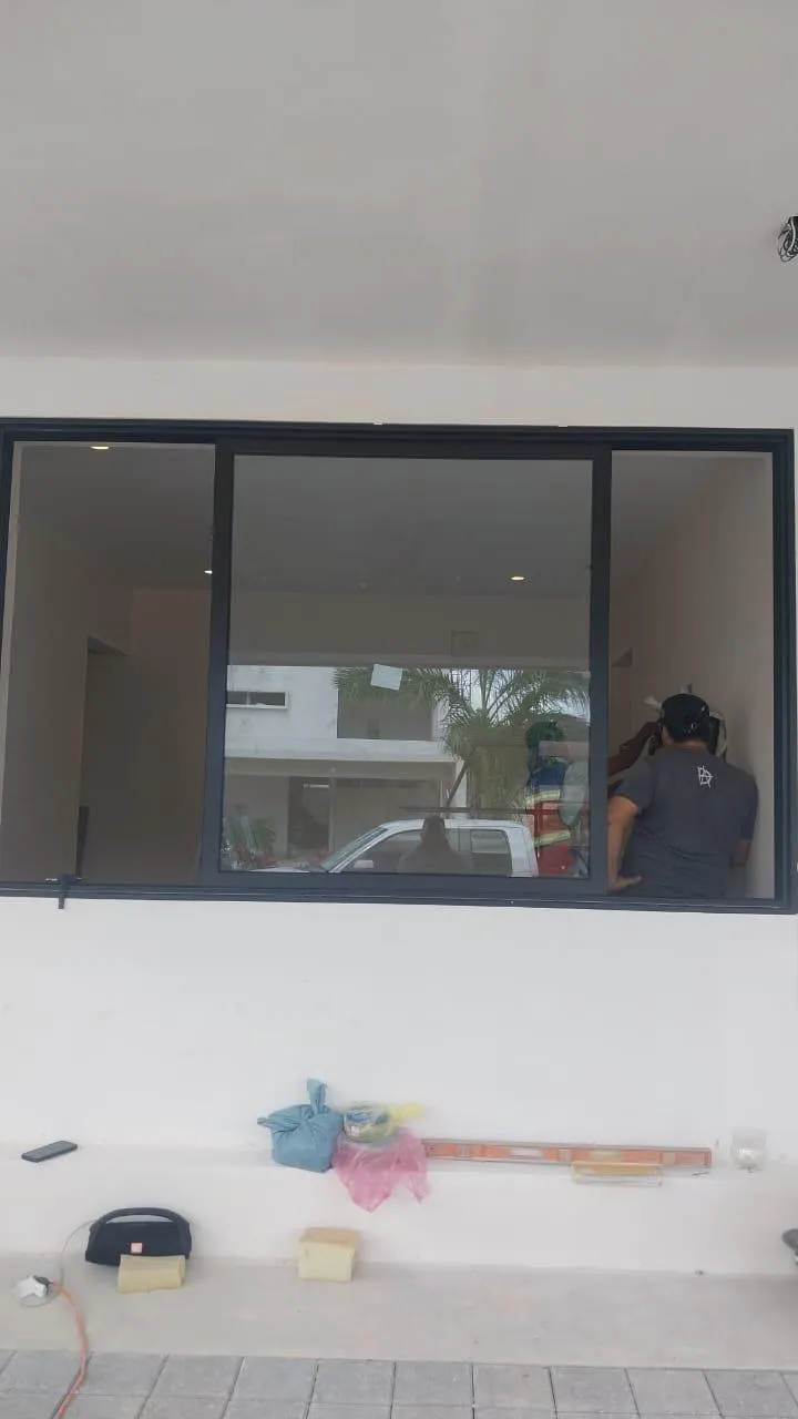 Instalación de ventana fija de aluminio negro con trabajador