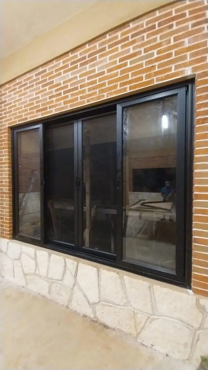 Ventana de aluminio negro de cuatro hojas en muro de ladrillo